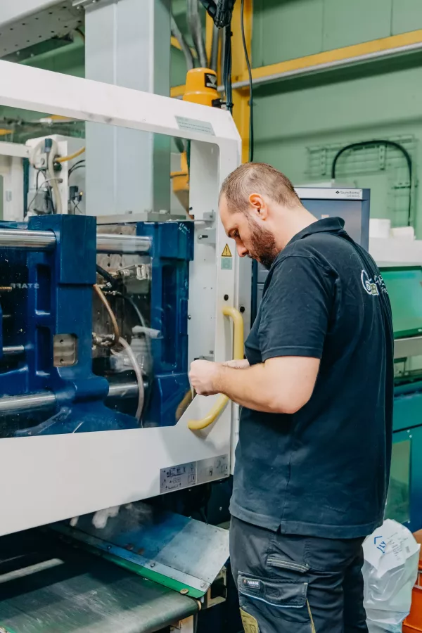 Opérateur sur une presse à injecter du plastique dans l'atelier de Sagaert Plasturgie